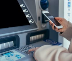 Woman using her phone at the ATM 